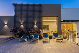 Una piscina al aire libre, sombrillas, sillones reclinables de piscina