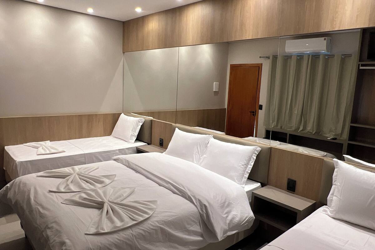 Ein Hotelzimmer mit zwei Betten, einem großen Spiegel und einer integrierten Klimaanlage.
