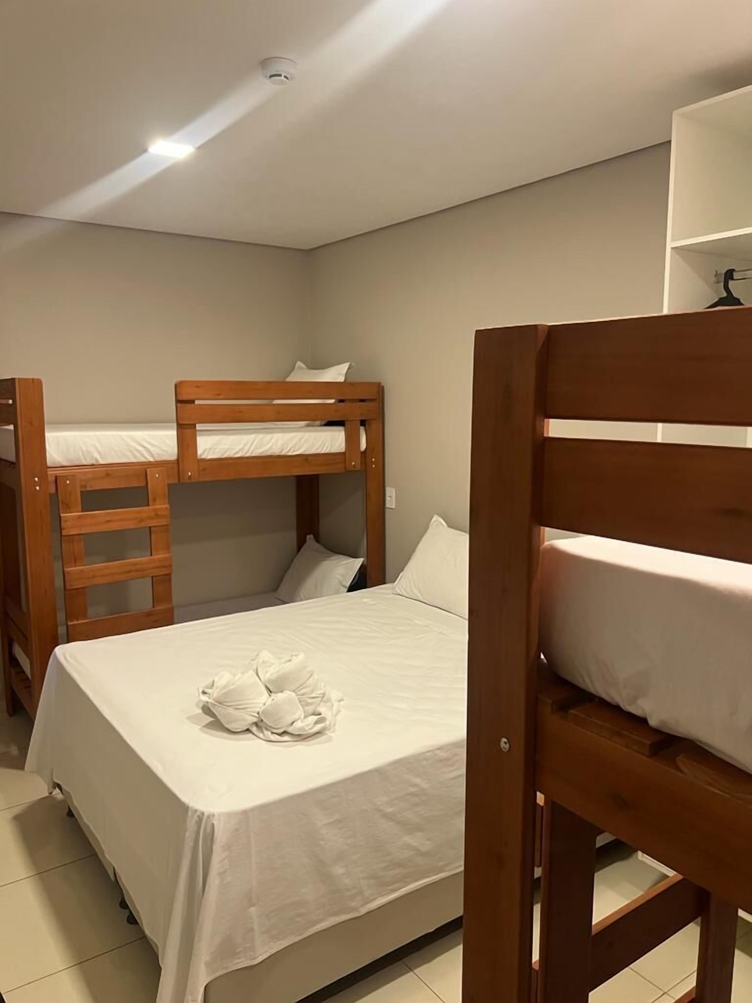 Un dormitorio con literas, una colcha blanca y una toalla en la litera inferior.