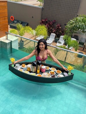 A woman seated at a poolside table with a variety of food and drinks. - Pousada Villas Bonito (Bonito)