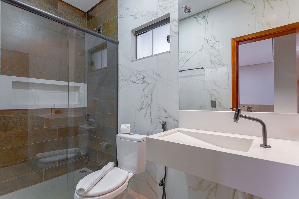 Ein modernes Badezimmer mit Duschkabine aus Glas, einer weißen Toilette und einer Wand mit Marmorfliesen.