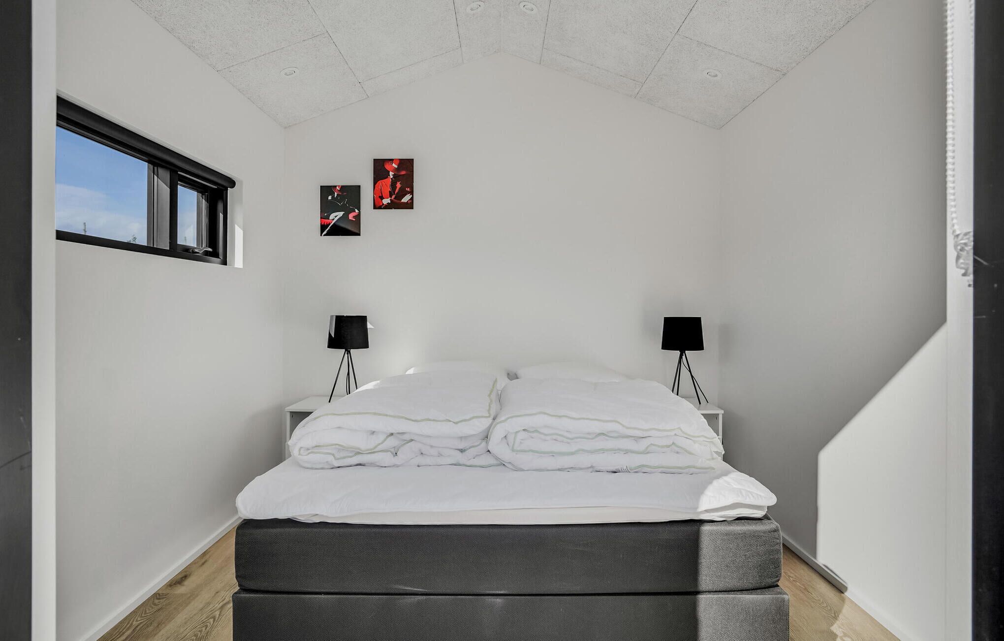 Una camera da letto con un letto, due lampade da comodino e due quadri appesi al muro.