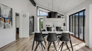 Uma cozinha moderna com área de refeições, destacando um grande janela, luminária pendente e relógio na parede.