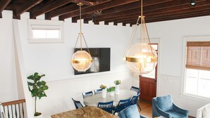 A dining area with a round table, blue chairs, and hanging pendant lights.