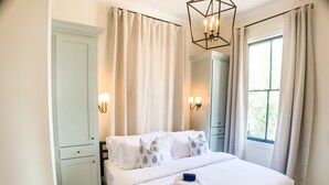 Un dormitorio con una cama, una mesita de noche, un aparador y una ventana con cortinas.