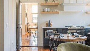 Una cocina moderna con armarios de madera, una mesa de comedor, sillas y un horno empotrado.
