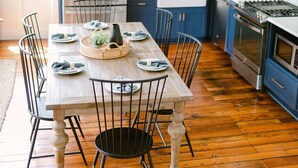A kitchen with blue cabinets, a wooden dining table set for six, and a stainless steel oven. - Guesthouse Charleston: EAST (46 H) (Charleston)