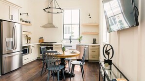 Een moderne keuken met een eethoek, roestvrijstalen apparatuur en een groot raam voor natuurlijk licht.