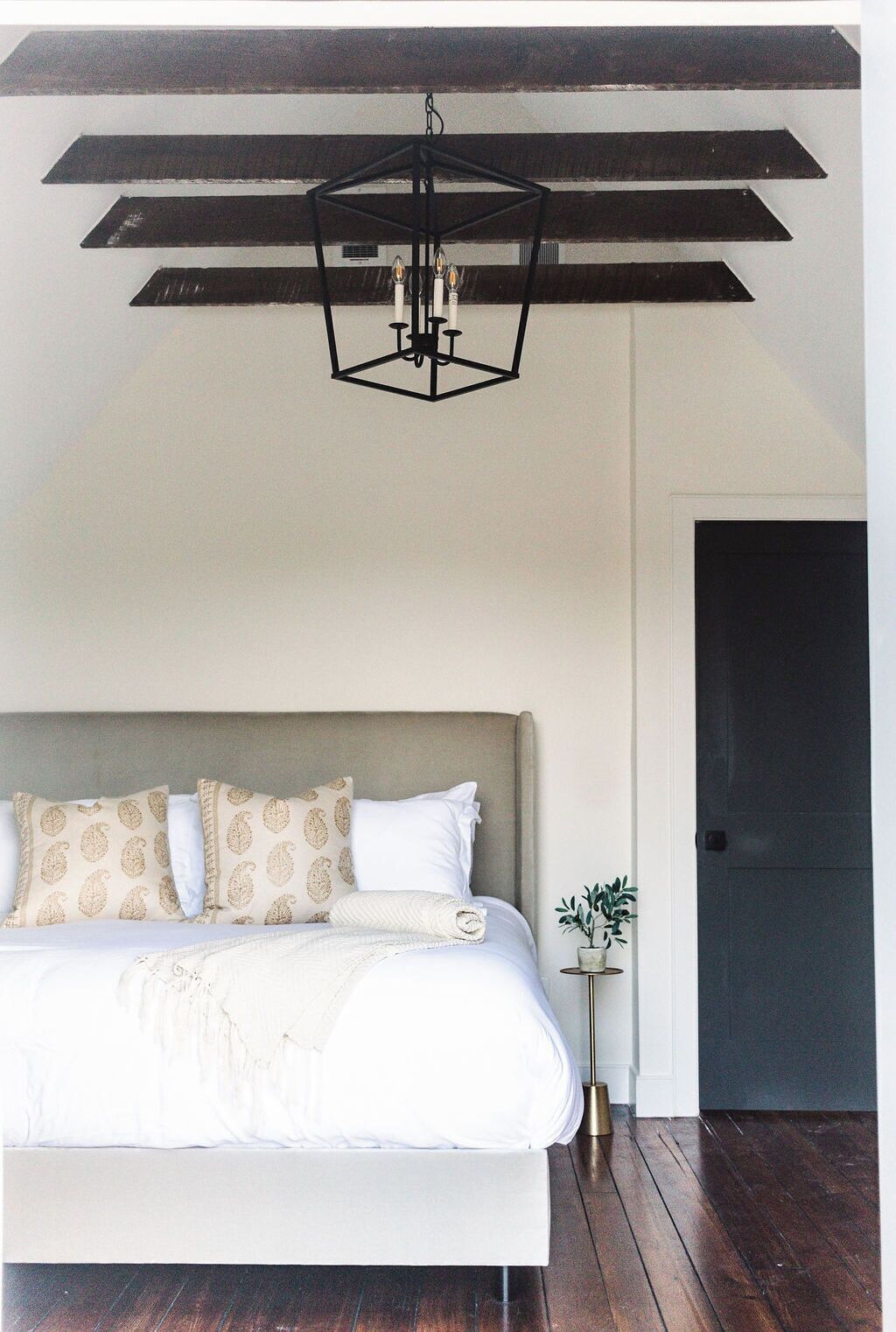 Een slaapkamer met een bed, een hanglamp en een deur.