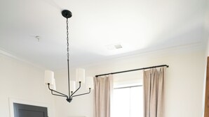 A bedroom with a large bed, a chandelier, a window with curtains, and a door. - EAST 46 G - 1 Block to King! (Charleston)
