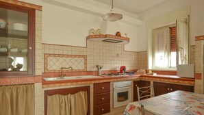A kitchen with a tiled backsplash, a stove, an oven, and a window with curtains. - Awesome apartment in Contrada Fiori Sud (Contrada Fiori Sud)