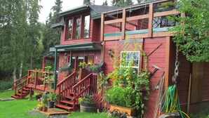 Una casa de madera roja con un porche, escalones y plantas en macetas.
