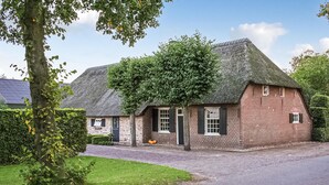 A traditional brick house with a thatched roof, a small front porch, and a well-maintained lawn. - 1 bedroom cozy home in Udenhout (Udenhout)
