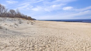 A sandy beach with a clear sky and a distant pier.