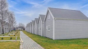A row of uniform, single-story buildings with pitched roofs, arranged in a linear fashion along a paved pathway.