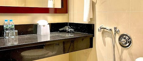 A modern bathroom with a black countertop, a sink, a mirror, a towel rack, and a shower.