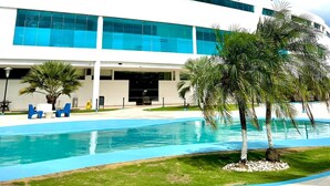 A modern hotel with a pool, featuring a large glass facade and a rooftop terrace.