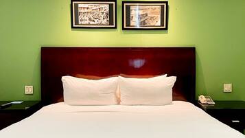 Een hotelkamer met een groot bed, groene wanden en twee ingelijste foto's aan de muur.