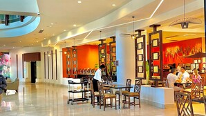 A spacious indoor area with a high ceiling, polished floors, and a variety of seating arrangements including tables and chairs.
