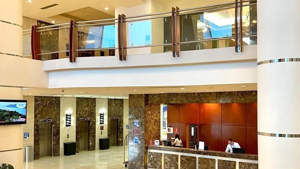 A spacious lobby with a reception desk, seating area, and a second-floor balcony.