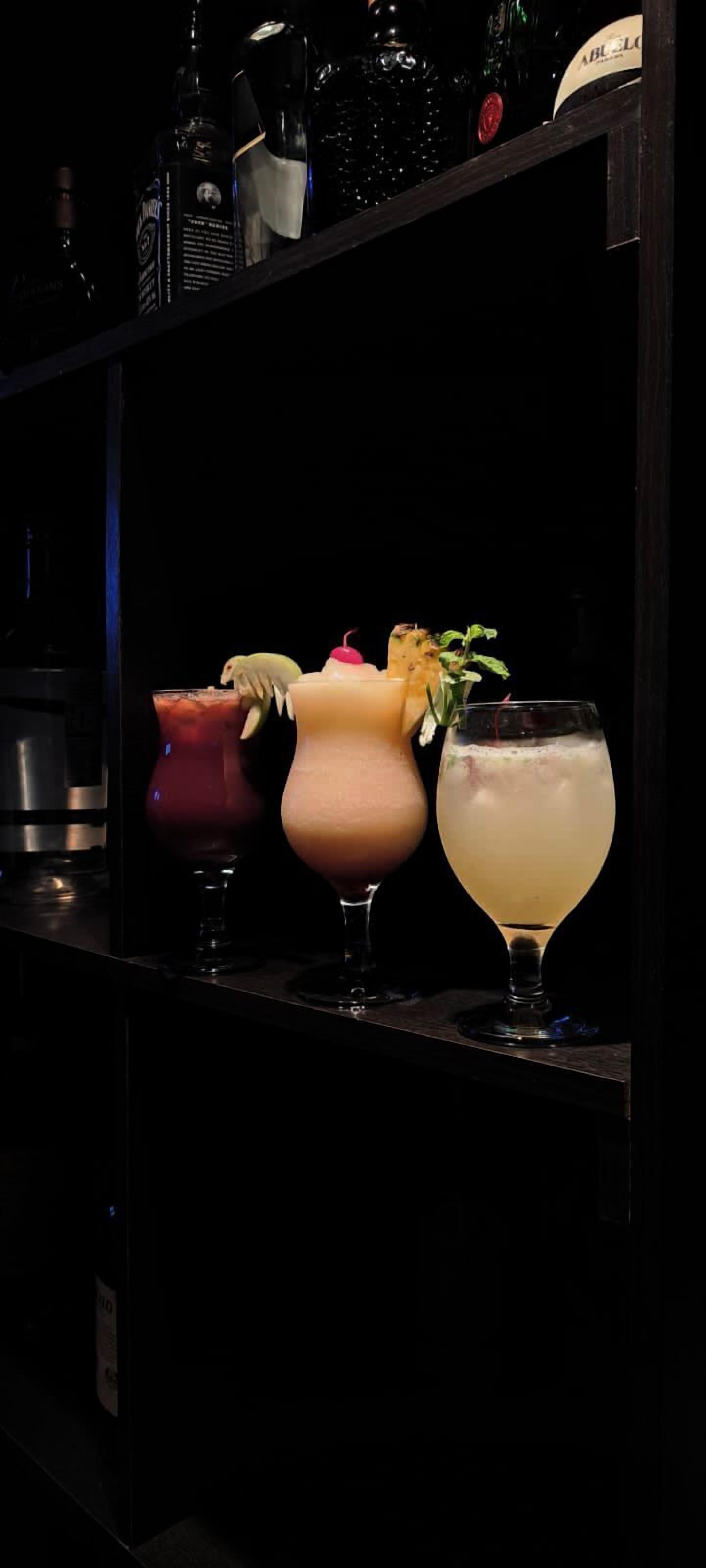 A bar area with three different types of drinks displayed on shelves.