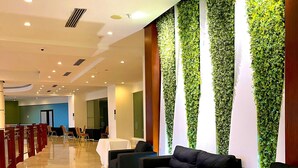 A modern lobby with a long reception desk, black sofas, and green vertical gardens.