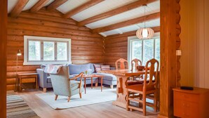 A cozy log cabin interior with a sofa, dining table, chairs, and a hanging light fixture. - Nice home in Kvam with kitchen (Kvam)