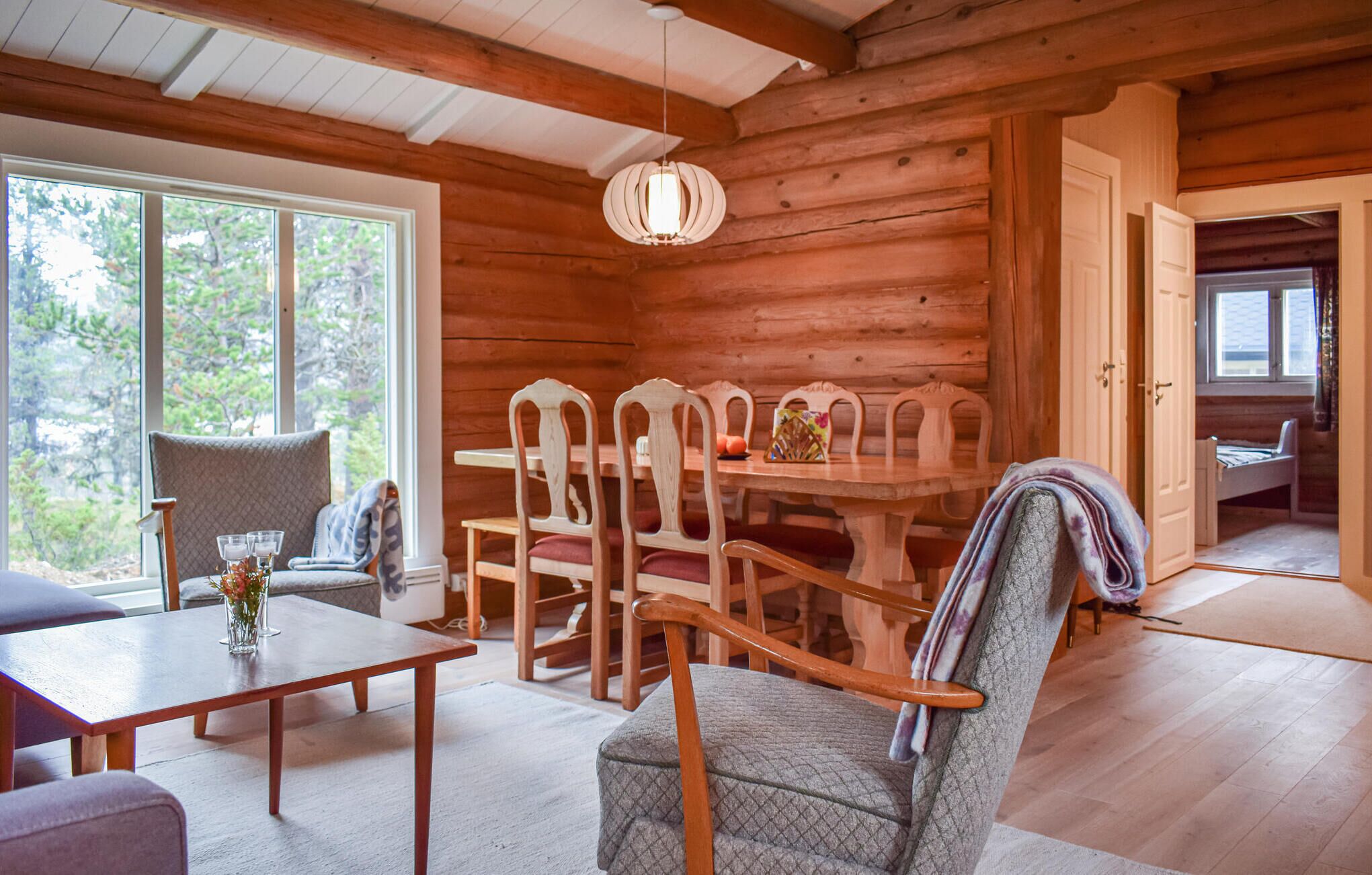 Interior acogedor de una cabaña con comedor, zona de estar con un sillón mullido y una cama en la esquina.
