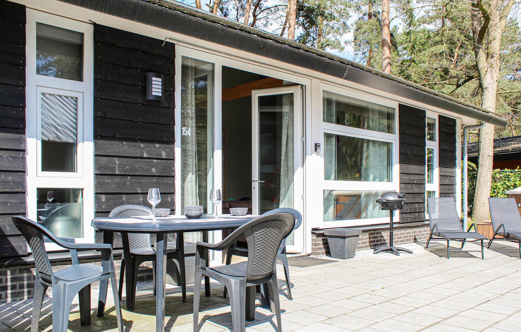 Une terrasse extérieure avec une table et des chaises, un barbecue et une vue sur les arbres environnants.