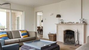 A modern living room with a sofa, a coffee table, a fireplace, and a dining area in the background. - Amazing home in Noordwijk aan Zee (Noordwijk aan Zee)