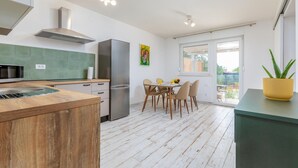 A modern kitchen with a wooden island, stainless steel appliances, and a dining area with a table and chairs. - Amazing home in Peroj (Peroj)