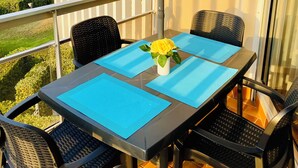 A balcony with a table, chairs, and a table umbrella.