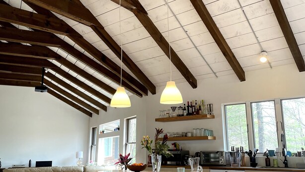 A spacious kitchen with a large island, wooden beams, pendant lights, and a view of the outdoors. - Catskills Family Hideaway (Olivebridge)