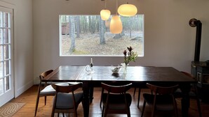 A dining area with a large window, wooden ceiling beams, and a table with chairs. - Catskills Family Hideaway (Olivebridge)