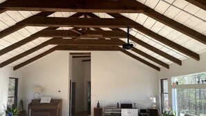 A spacious living room with a high ceiling, wooden beams, a piano, a sofa, and a television. - Catskills Family Hideaway (Olivebridge)