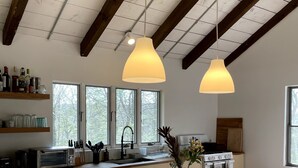 A modern kitchen with a large island, pendant lights, a built-in oven, and a wine rack. - Catskills Family Hideaway (Olivebridge)