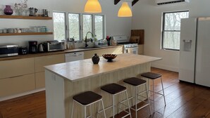 A modern kitchen with a central island, bar stools, and a hanging pendant light. - Catskills Family Hideaway (Olivebridge)
