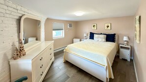 A bedroom with a bed, dresser, and a large mirror.
