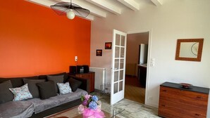 A modern living room with a sofa, a coffee table, and a cabinet. There is a door leading to another room. - Rent House Puyôo 8 people (Puyoo)