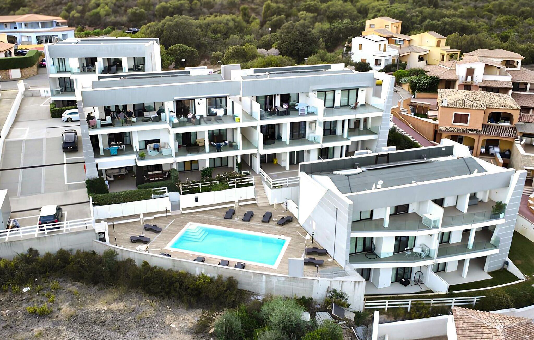 A modern multi-story hotel with a rooftop pool and outdoor seating areas.