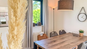 A dining area with a wooden table, chairs, a lamp, and a clock on the wall.