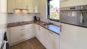 A modern kitchen with white cabinets, a wooden countertop, a built-in oven, and a window with a view of the outside.