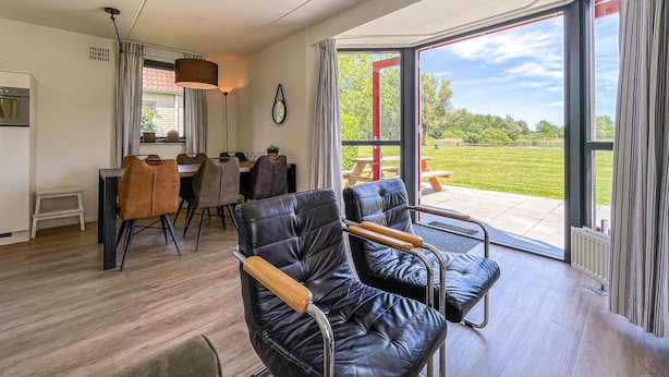 A modern room with a dining area, a large window with a view of the outdoors, and a black leather chair.