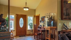 A spacious living room with a wooden dining table, chairs, and a glass display case with decorative items. - THE BIRDHOUSE,... Quiet Country Home in the Bitterroot Valley. (Florence)
