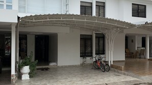 A two-story building with a covered patio area, a bicycle, and a potted plant. - Hostal Lucy (Valledupar)