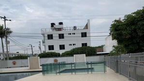 A spacious outdoor area with a swimming pool, a gated entrance, and a modern building in the background. - Hostal Lucy (Valledupar)