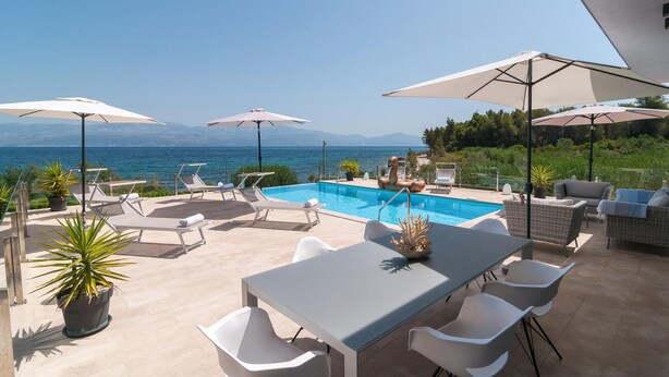 An outdoor pool area with lounge chairs and umbrellas, overlooking a body of water and mountains. - Luxurious home in Sutivan (Sutivan)