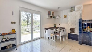 Eine moderne Küche mit Essbereich, ausgestattet mit einem großen Fenster, weißen Schränken und einer gefliesten Spritzschutzwand.