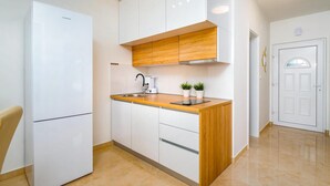 A modern kitchen with white cabinets, a wooden countertop, a built-in oven, and a coffee maker. - 2 bedroom beach front apartment in Banjol (Banjol)
