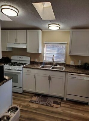Kitchen features a gas stove, oven, dishwasher, and sink with a window above.